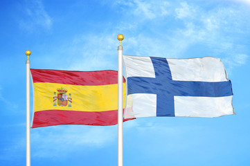 Spain and Finland two flags on flagpoles and blue cloudy sky