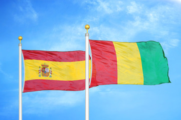 Spain and Guinea two flags on flagpoles and blue cloudy sky
