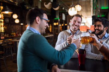 Group of happy friends having fun and drinking beer at pub