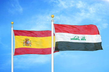 Spain and Iraq two two flags on flagpoles and blue cloudy sky