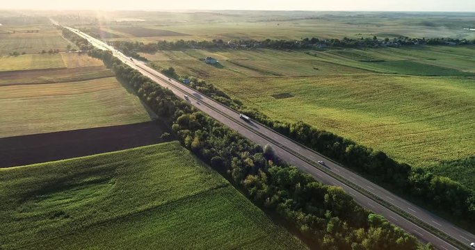 Highway between fields at sunset