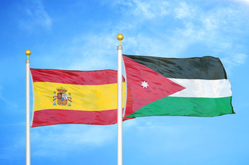 Spain and Jordan two flags on flagpoles and blue cloudy sky