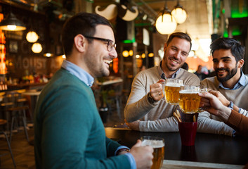 Group of happy friends having fun and drinking beer at pub