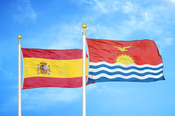 Spain and Kiribati two flags on flagpoles and blue cloudy sky