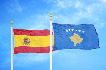 Spain and Kosovo two flags on flagpoles and blue cloudy sky