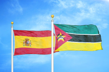 Spain and Mozambique two flags on flagpoles and blue cloudy sky