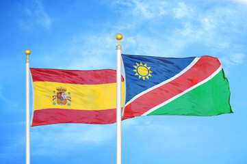 Spain and Namibia two flags on flagpoles and blue cloudy sky