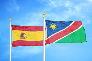 Fototapeta premium Spain and Namibia two flags on flagpoles and blue cloudy sky