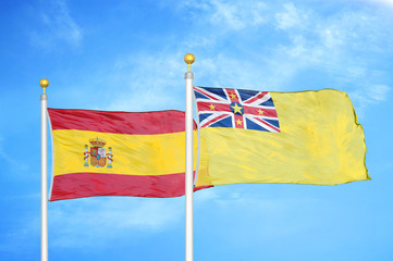 Spain and Niue two flags on flagpoles and blue cloudy sky