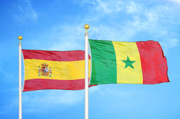 Spain and Senegal two flags on flagpoles and blue cloudy sky