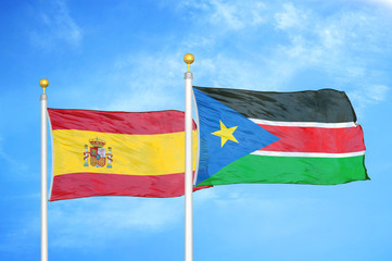 Spain and South Sudan two flags on flagpoles and blue cloudy sky