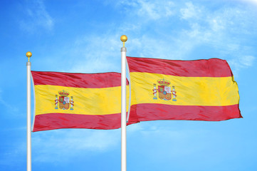 Spain two flags on flagpoles and blue cloudy sky