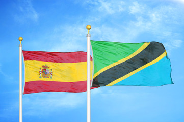 Spain and Tanzania two flags on flagpoles and blue cloudy sky