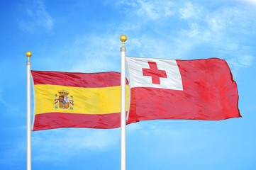 Spain and Tonga two flags on flagpoles and blue cloudy sky