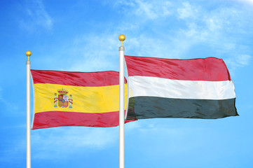 Spain and Yemen two flags on flagpoles and blue cloudy sky