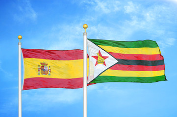 Spain and Zimbabwe two flags on flagpoles and blue cloudy sky