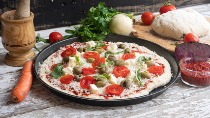Raw homemade Pizza and Ingredients on white wooden table, top view