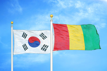 South Korea and Guinea two flags on flagpoles and blue cloudy sky