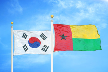 South Korea and Guinea-Bissau two flags on flagpoles and blue cloudy sky