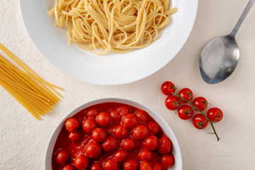Overhead of Plate of Cooked Pasta and Bowl of Tomato Sauce