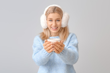 Beautiful young woman with cup of tea on grey background