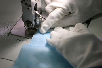 The woman is using a machine to filter the lining of a surgical mask. A close-up