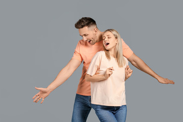 Happy dancing young couple on grey background