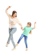 Happy mother and her little daughter dancing against white background