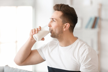 Young man drinking milk at home