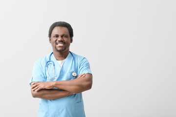 Male African-American doctor on light background