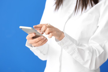 Beautiful young woman with mobile phone on color background, closeup