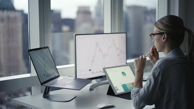 Skilled female marketer with electronic stylus analyzing commerce data infographics during work with online platform blockchain, professional woman reading diagram info about bitcoin crypto currency
