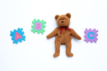 Bear toy with english alphabet puzzle on blue background. Education concept