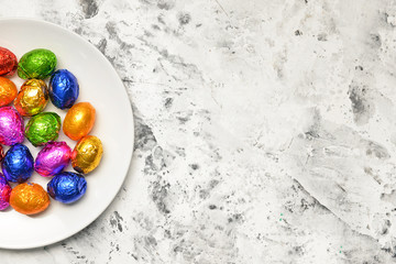 Plate with sweet chocolate eggs on light background