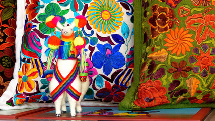 Close up of сolorful embroidered decorative pillows, textiles and souvenir llama at the artisan's market in Otavalo, Ecuador