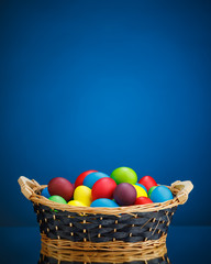 Easter color eggs in festive gift basket, blue background
