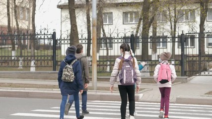 School children cross the road in medical masks. Children go to school - Powered by Adobe