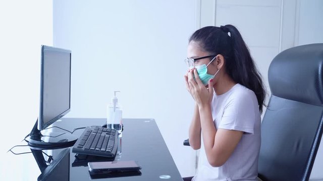 Young woman wearing a mask and hand sanitizer to prevent corona virus before working with computer at home. Shot in 4k resolution