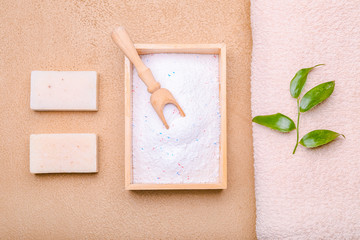 Towel, soap and laundry detergent on color background