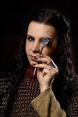 A dark-haired woman with a dirk, a Scandinavian warrior in a chain mail against a dark background