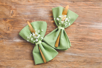 Napkins with cutlery and floral decor prepared for table setting on wooden background