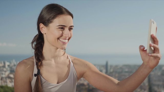 Woman taking selfie photo on smartphone. Girl showing peace sign at phone camera