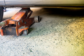 The orange hydraulic jack is lifting the car