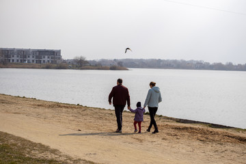 A man and a woman with a child are walking on a sandy shore. During Quarantine