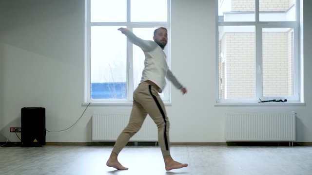 man jumping in dance in a dance studio by the window