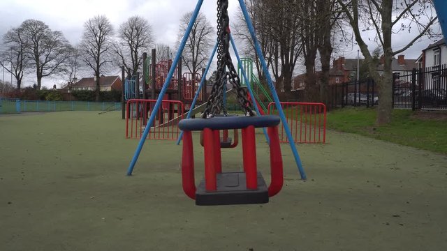 Childrens swing in empty public playground during Coronavirus Pandemic. April. West Midlands. UK