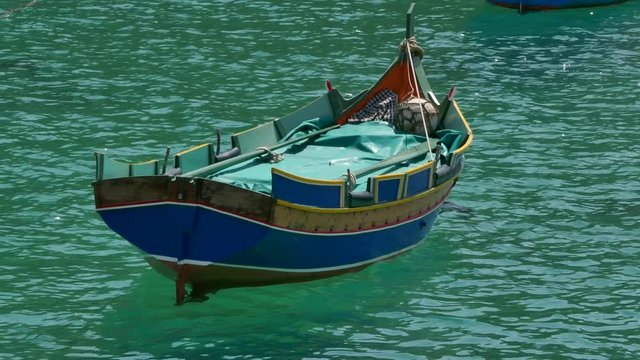 A traditional Maltese boat Dgħajsa floating on turquoise water in Malta