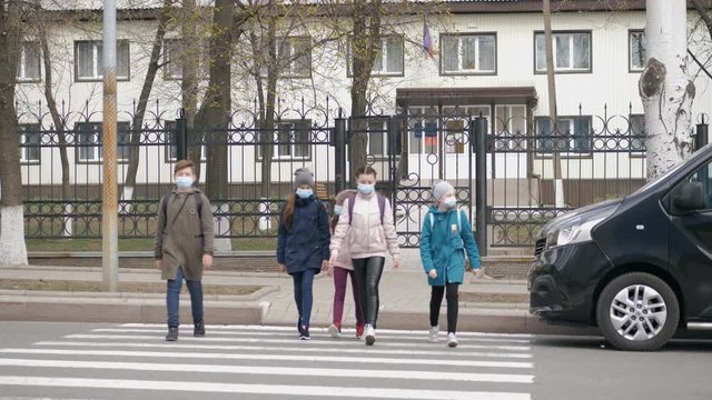 School children cross the road in medical masks. Children go to school