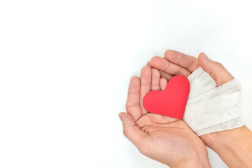 Injured cupped hands holding a red heart. Unconditional love, sacrifice and compassion.