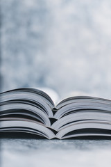 education and self-improvement, pile of open books shot from eye level with shallow depth of field